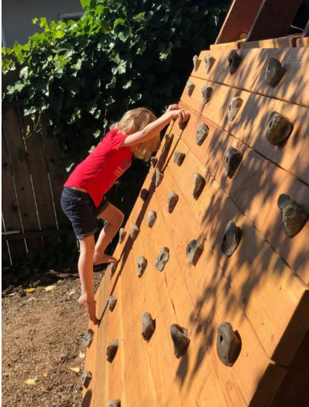 A child is on a rock-climbing wall scaled just for children