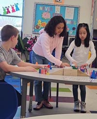 School-age kids play a came at a round classroom table.