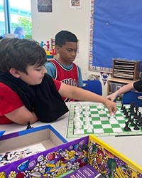 Children playing chess in a classroom.