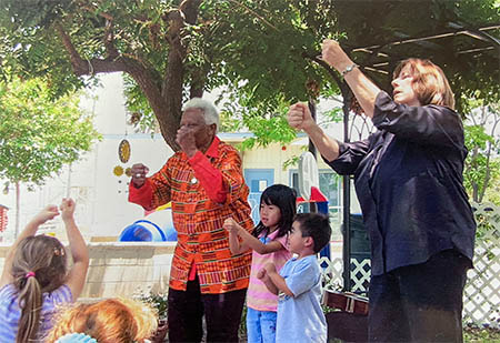 Ella Jenkins and Chris Lamm perform outside with two children helpers.