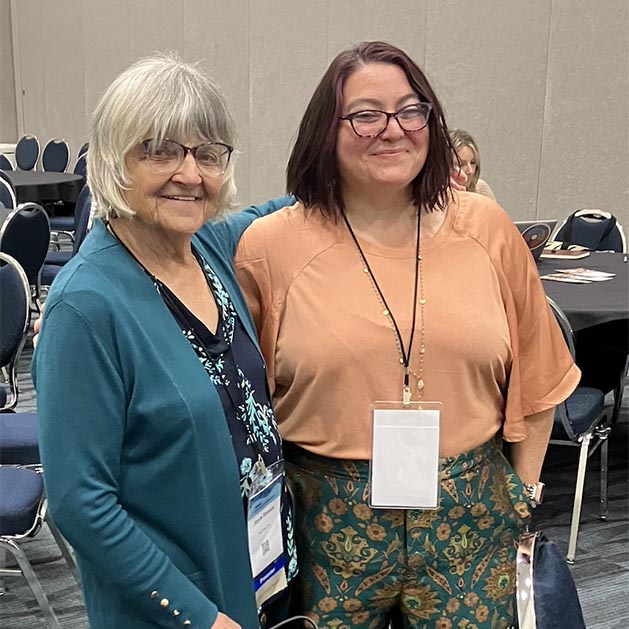 Joyce Daniels and Monica Moran pose for a photo in a conference room