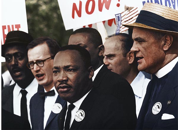 Martin Luther King Jr. surrounded by other men, black and white, at a protest march