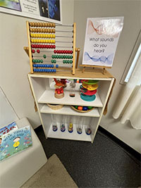 A book shelf with a variety of sensory elements, including an abacus, noise makers, and toys that light up.