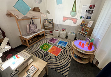 A corner set up for small children with a rug, sensory tiles, and other items to create a sensory studio