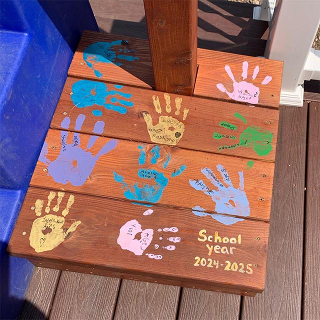 Base of a wooden podium with children's handprints in colorful paint.