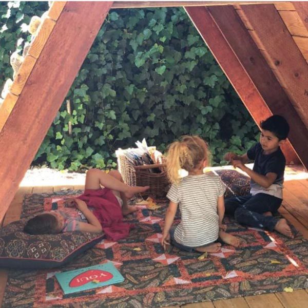 Children play inside an A-frame building scaled just for kids