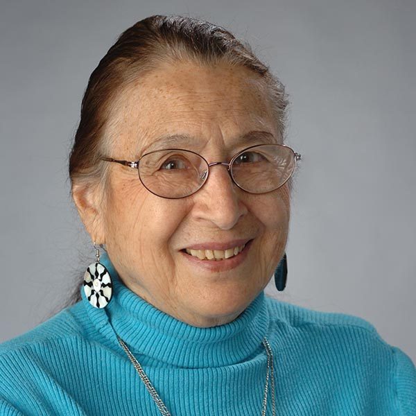 An older Native American woman wearing glasses and her hair in a bun.