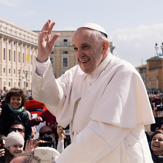 Pope Francis standing up to wave at the crowds of worshippers.