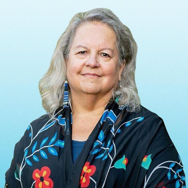 Headshot of an older caucasian woman with shoulder-length grey hair in a colorful, floral shirt.