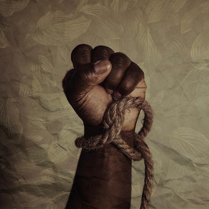 A black man's clenched fist with a rope around the wrist.