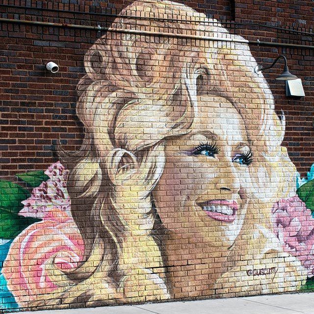 A mural of Dolly Parton painted on a brick wall. There are flowers all around her hair.