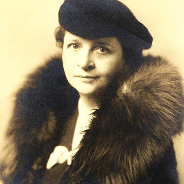 Sepia-toned photo of a women in a beret and fur-cuffed coat