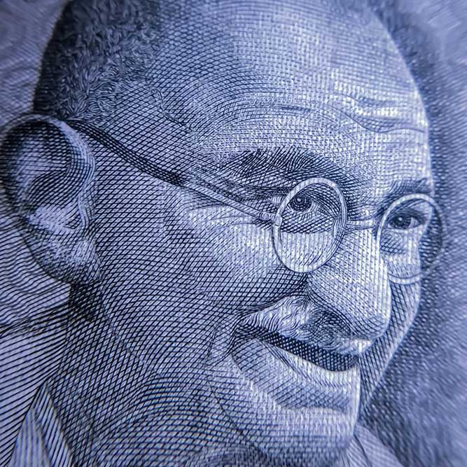 A blue, white and black engraved portrait of Mohandas Gandhi