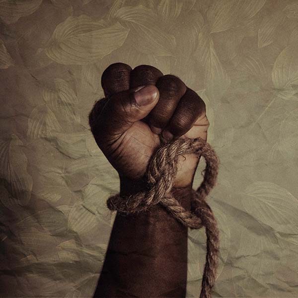 A Black man's clenched fist with a loose rope around the wrist