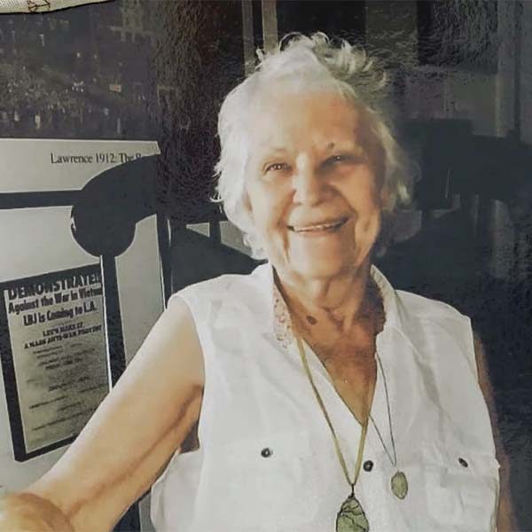 Older Caucasian woman with short white hair wearing a sleeveless shirt.