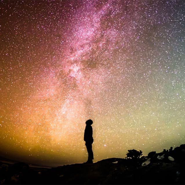 Silhouette of a child against a bright moon and stars