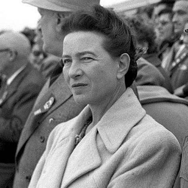 black-and-white cropped photo of Simone de Beauvoir in 1955 standing in a crowd of men in suits