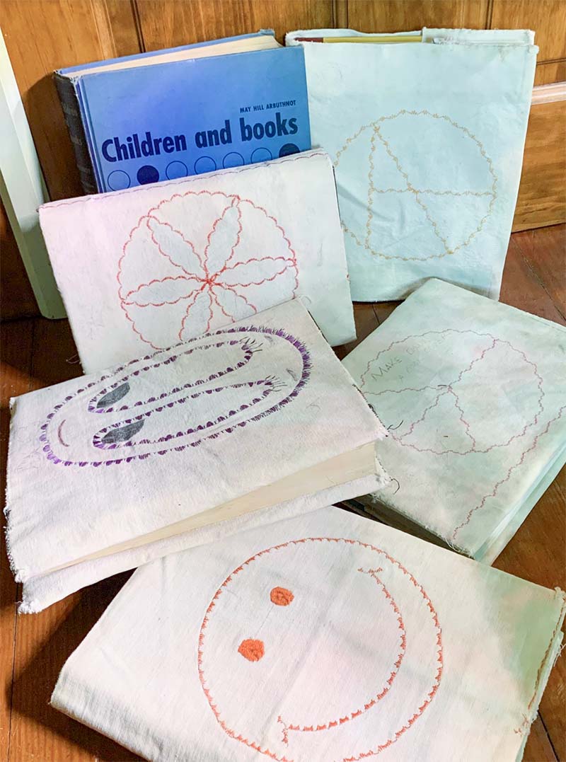 School books covered in handmade canvas covers decorated with embroidered stitching