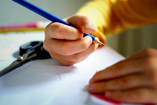 Close up of a child's hand holding a pencil over a piece of paper.