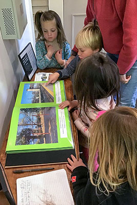 Pre-school children looking through a photo book at the gallery