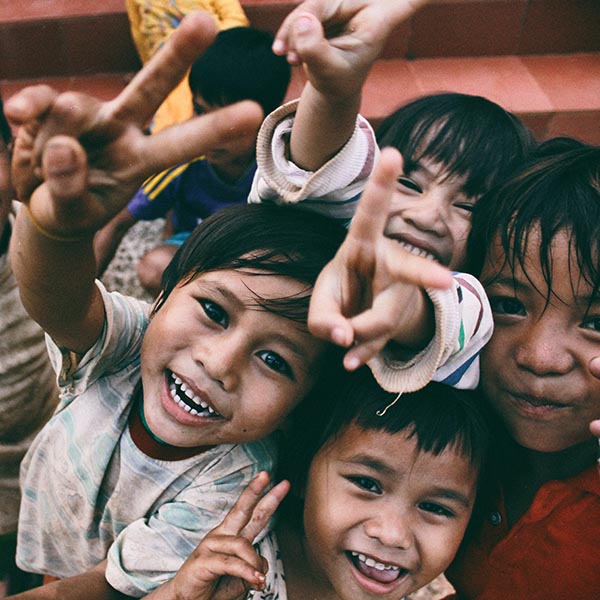Happy Vietnamese children looking up at the camera smiling and holding up their fingers in the peace sign