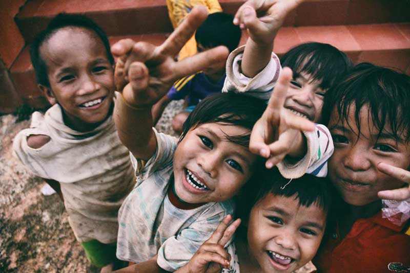 Downward perspective on a group of young south asian children making peace signs with their fingers