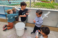 Preschool children helping during construction with plastic buckets and pieces of plastic pipe