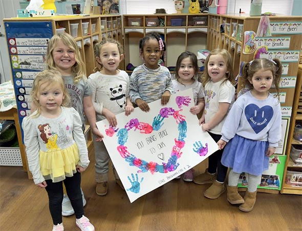 Seven K through grade 2 girls pose with their kindness poster.