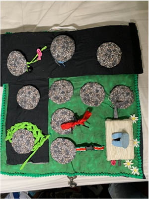 Felt, fabric scraps, yarn, zippers, and ribbons are sewn together to create a "manhole cover" board game.