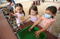 3 young girls wash up after cooking in the outdoor mud kitchen