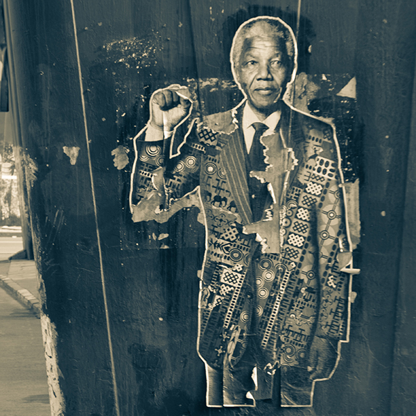 A black-and-white collage of Nelson Mandela raising a fist up at shoulder-height.
