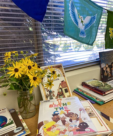 A desk with piles of children's books selected at the annual PEACE board retreat.
