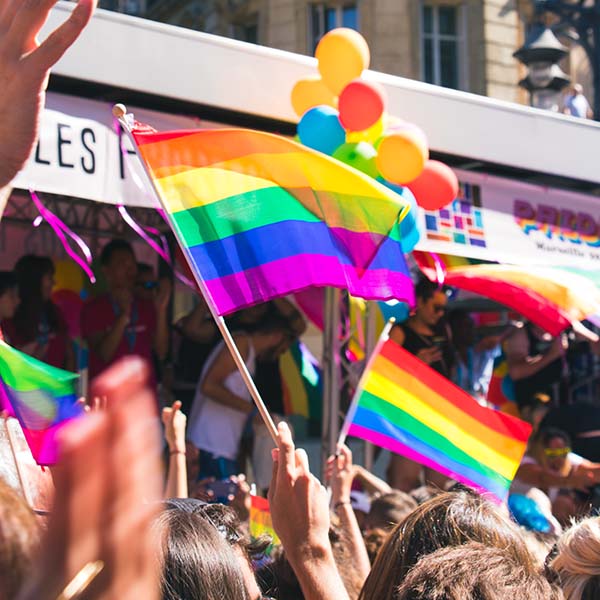 View of the tops of heads and rainbow flags and balloons at a Gay Pride parade