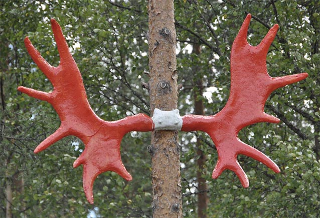 Red ceramic moose antlers glued to a tree trunk