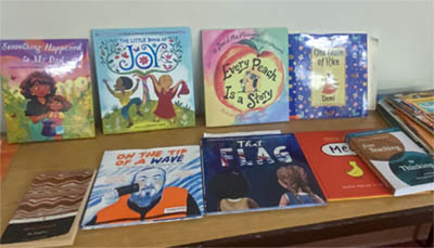 Children's books on display, including Something Happened to my Dad, The Little Book of Joy, Every Peach is a Story, One Grain of Rice, On the Tip of the Wave, and That Flag.