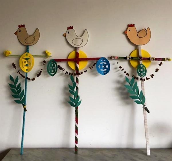 Handcrafted paper and stick art with roosters, eggs, and spring greenery celebrating Easter