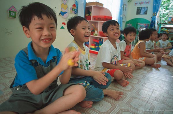 Young Asian boys seated on the floor of a classroom