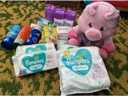 Diapers and other baby supplies next to a stuffed pig doll